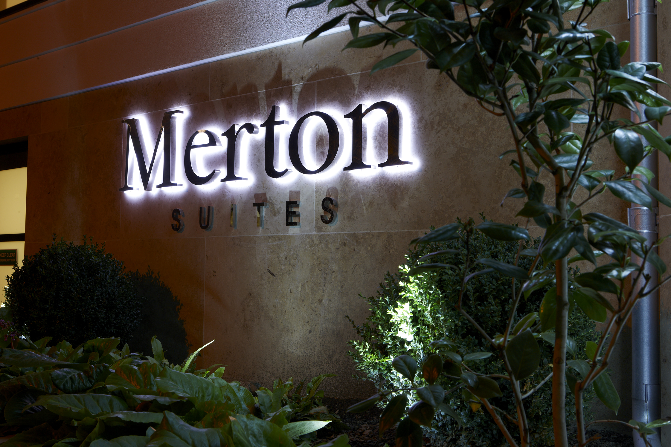Merton Suites sign lit up at night. 