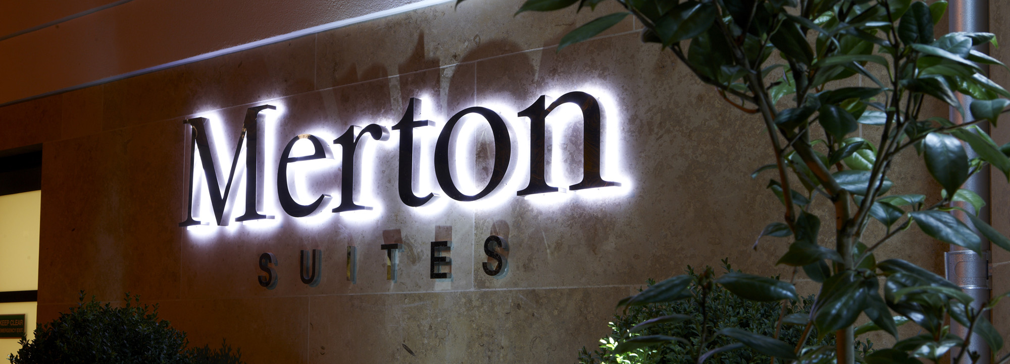 Merton Suites sign lit up at night.