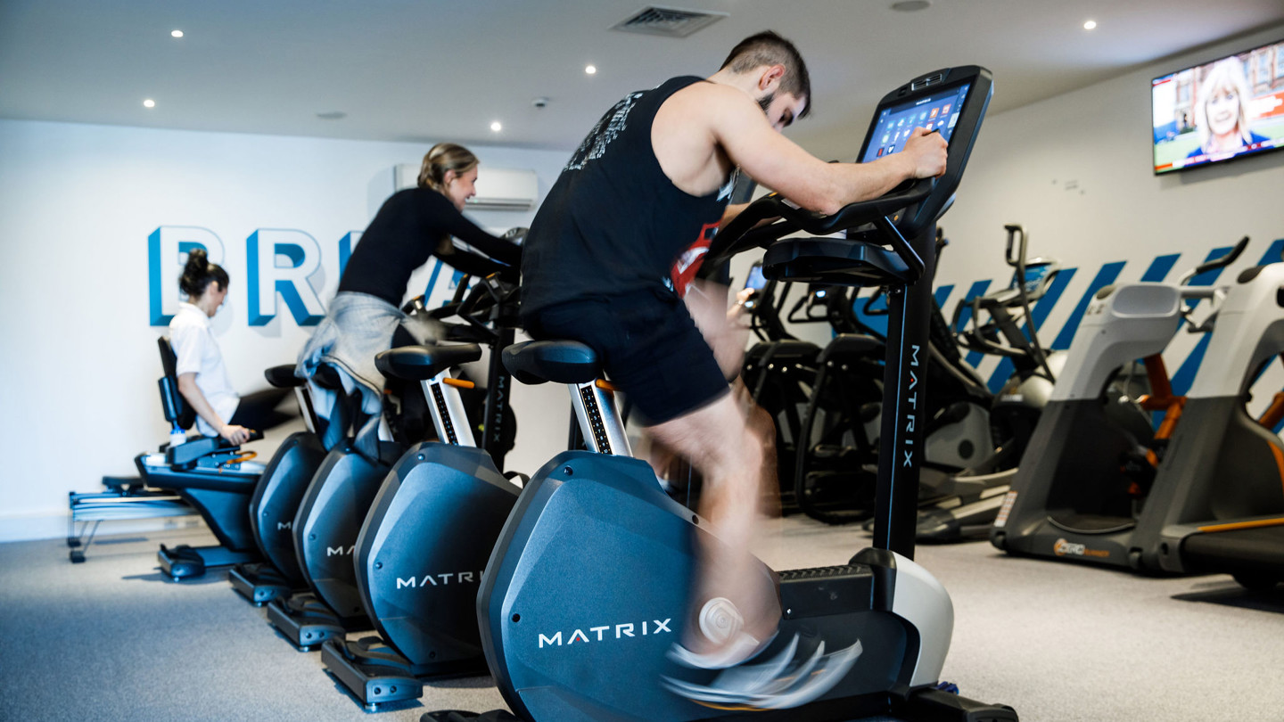 Two people use fitness bikes