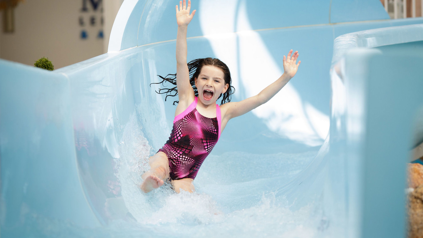 Young girl rides the flumes with her hands in the air