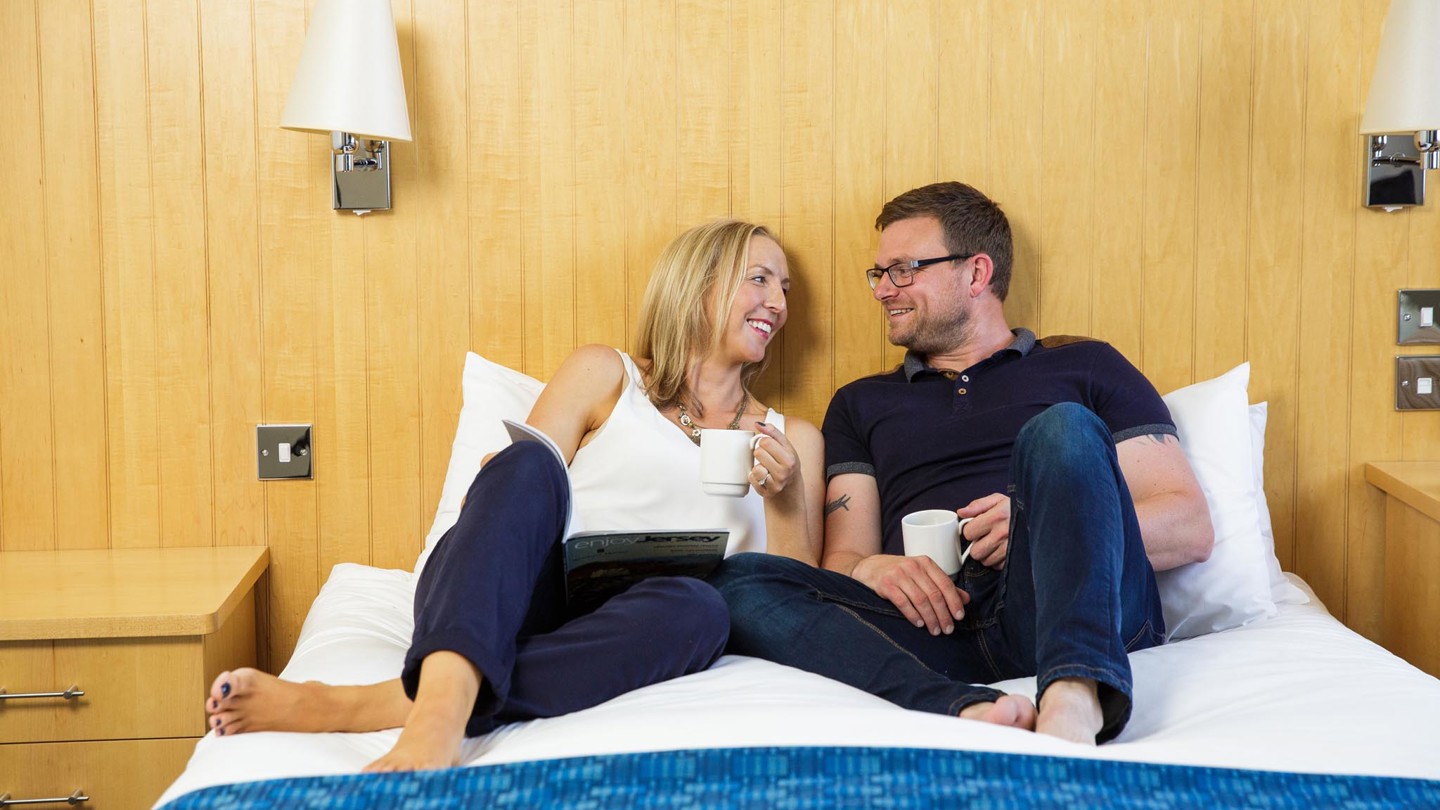 Couple talking over tea on a double bed